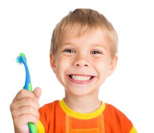 A boy smiling and holding a toothbrush proudly.